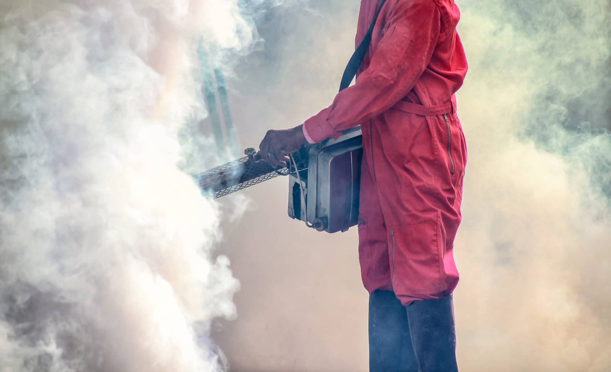 Man in red protective gear, fumigating.